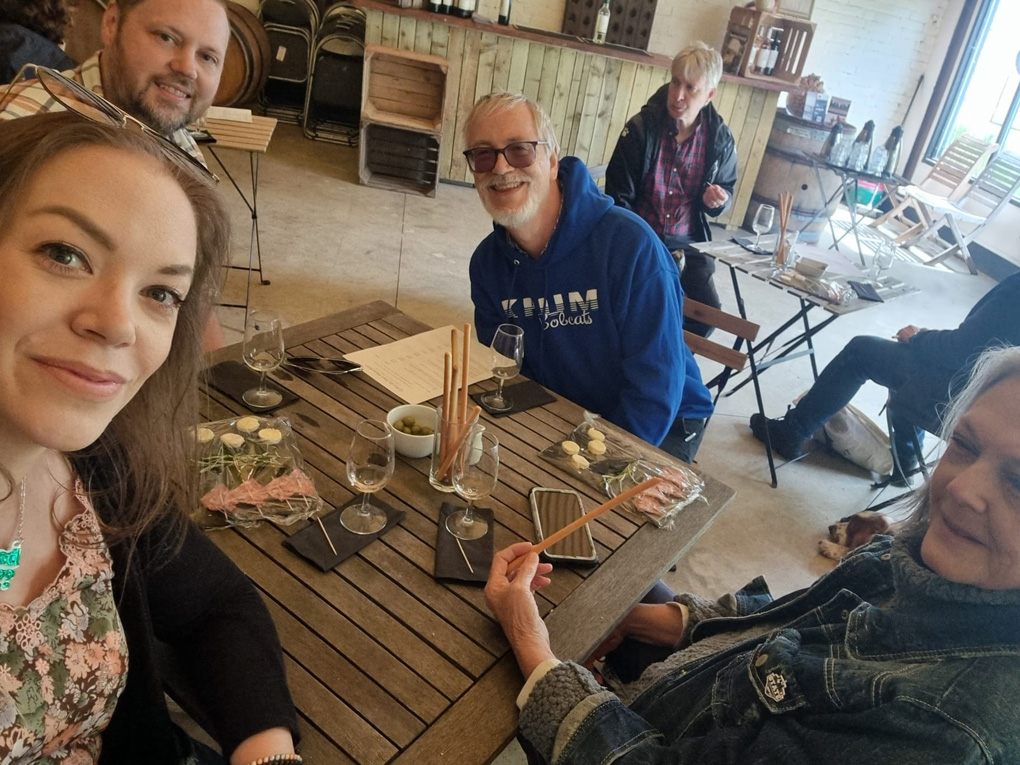 Adults around a table eating food and drinking wine