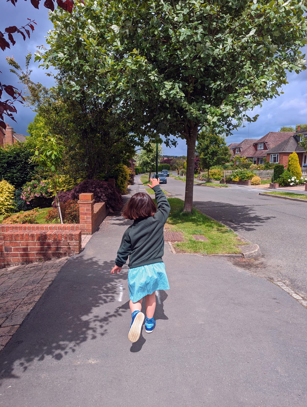 A young girl in school uniform running down the road