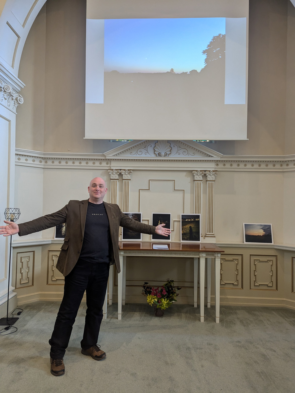 Man standing in front of photographs and a projector screen