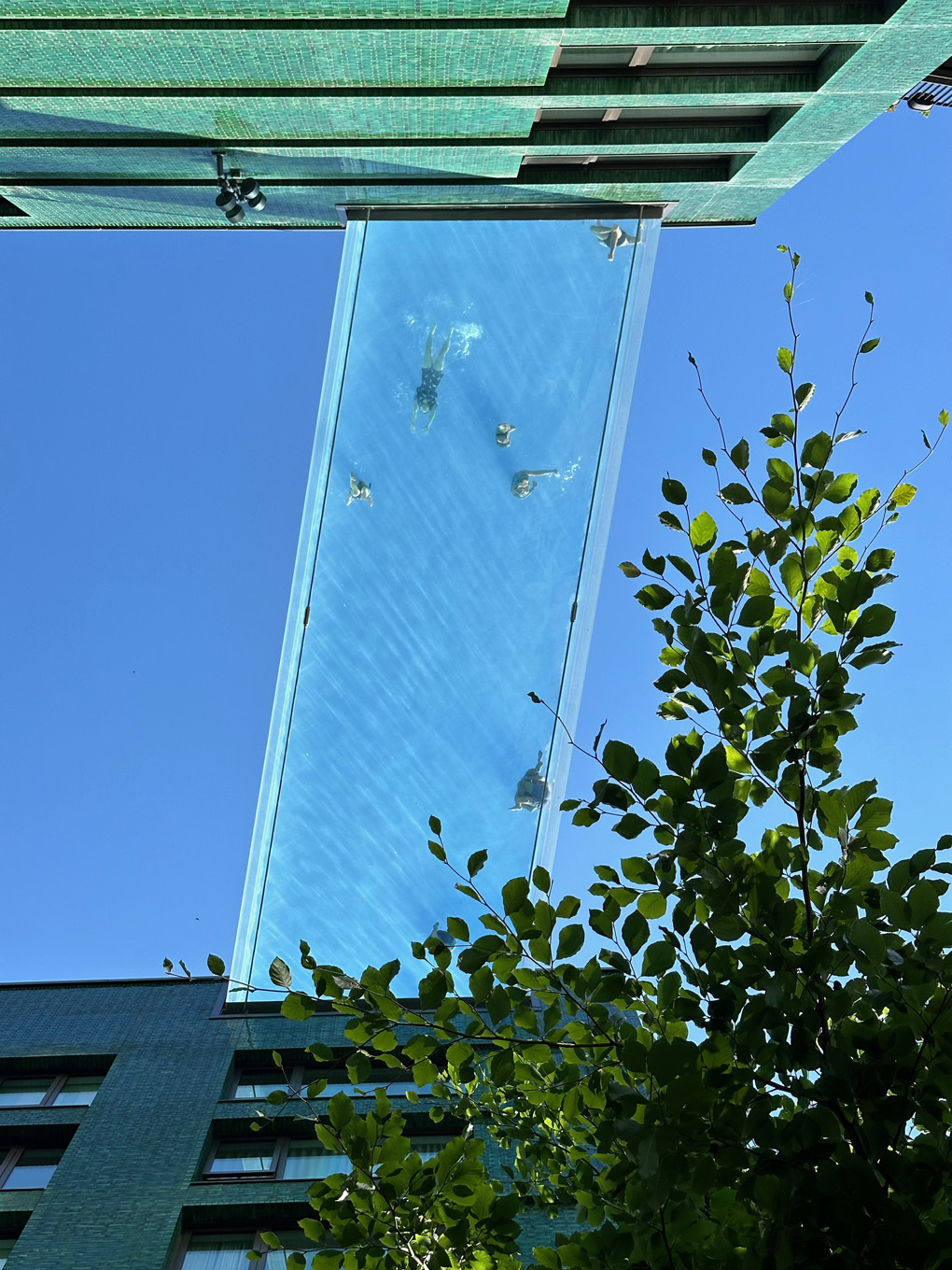 A swimming pool suspended between a couple of tall buildings. Shot from below.