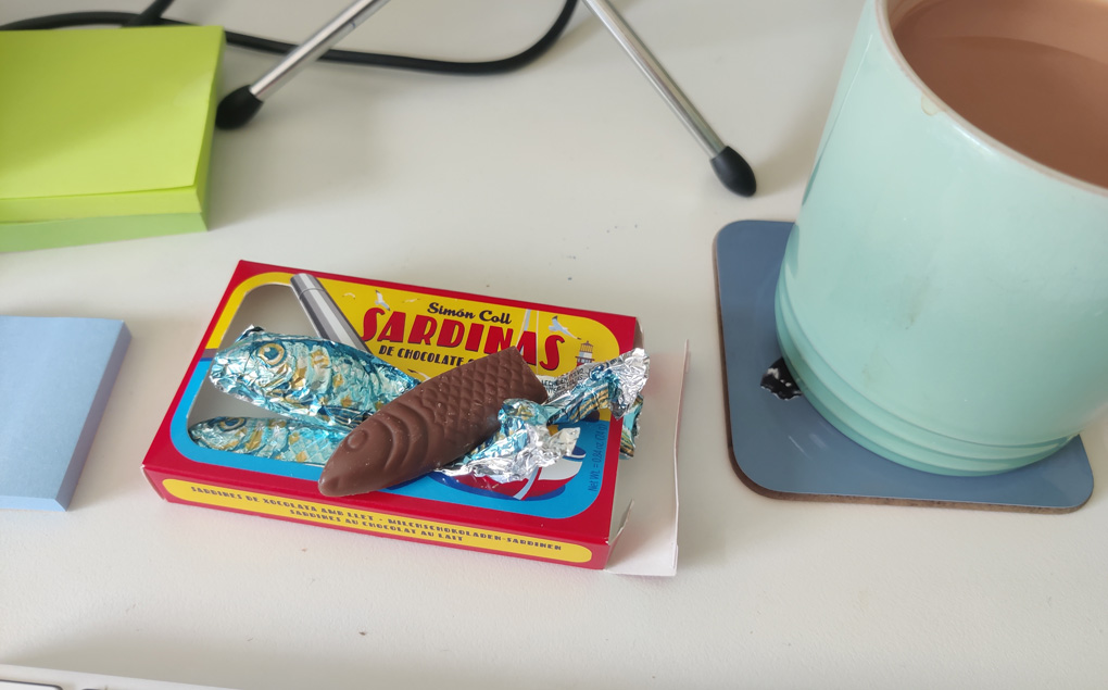 A small cardboard box decorated to look like a colourful Iberian sardine tin but instead of sardines these are little sardine shaped chocolates in shimmering scaly foil