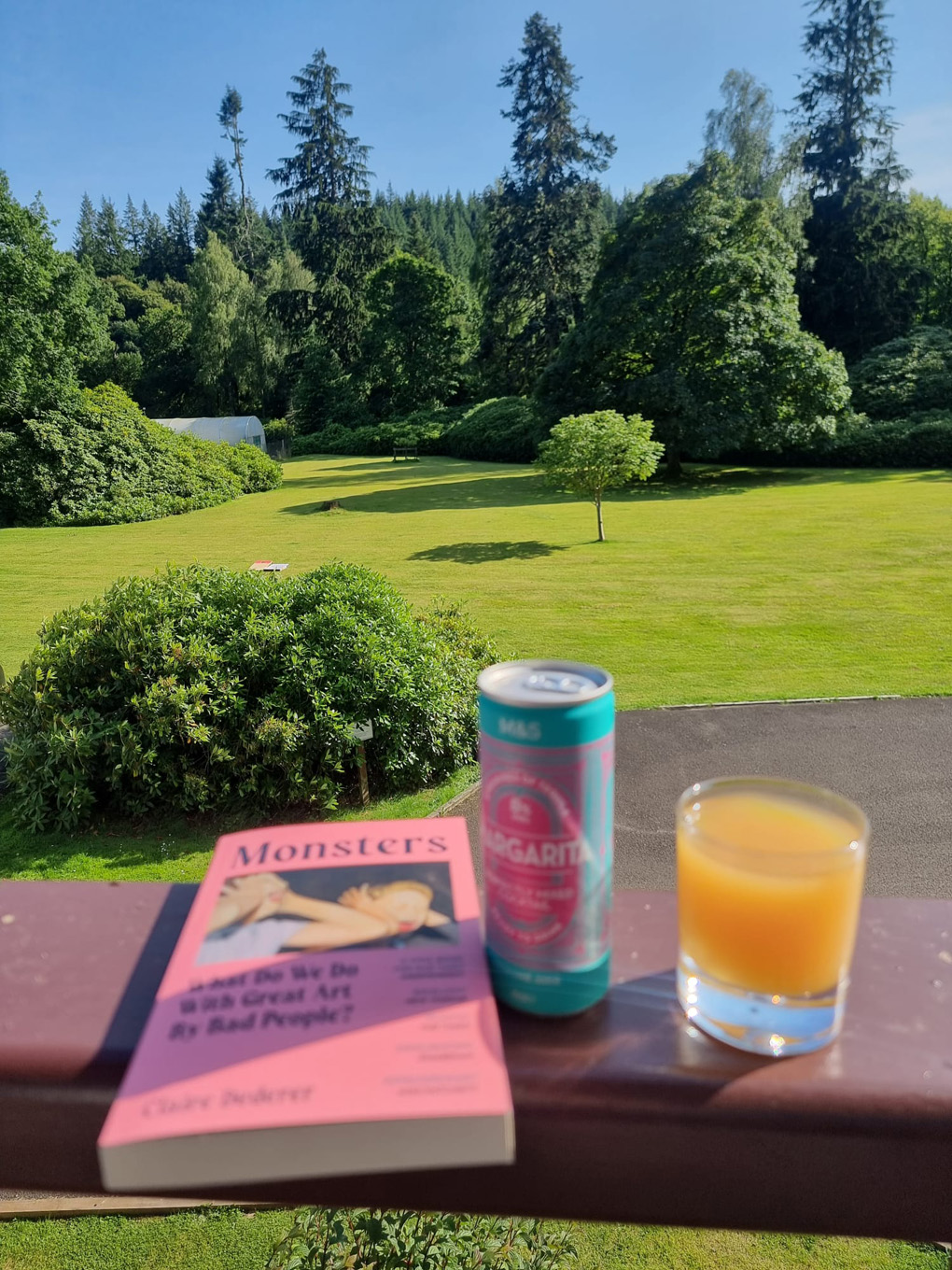 View across a green golf course with a book and drink in the foreground.