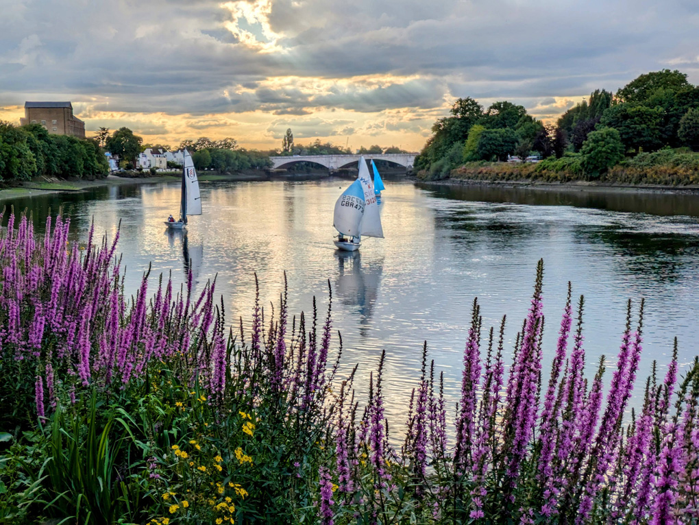 boats on the river Thames with the sunset and clouds in the background.