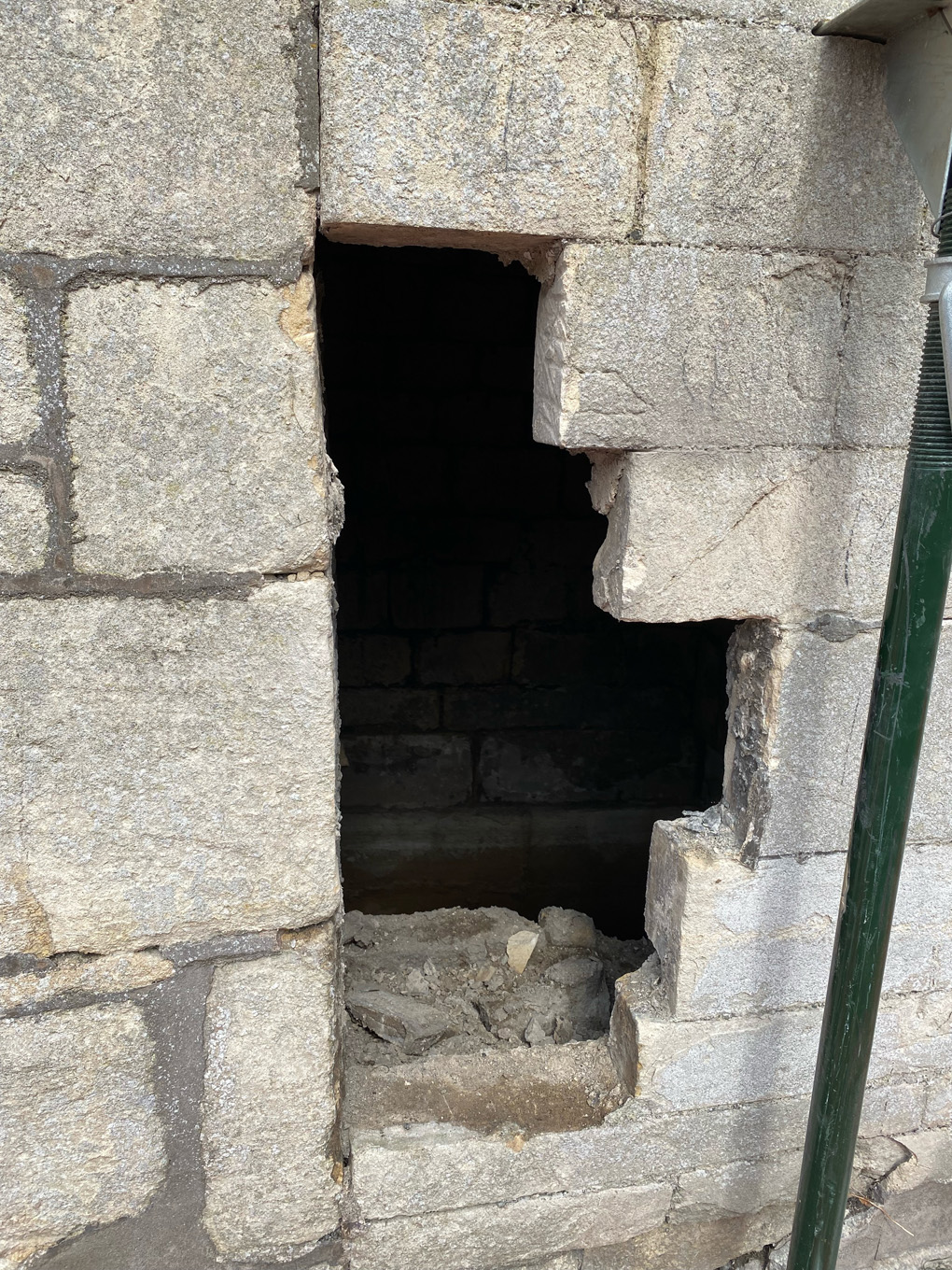 A gap in a stone wall, revealing an ominous dark space behind it