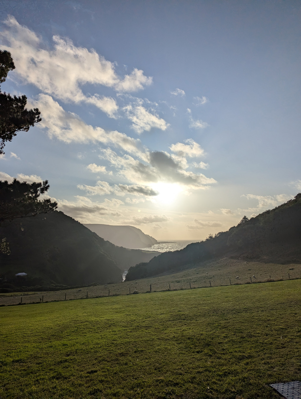 View down a valley over the sea as the sun starts to dip