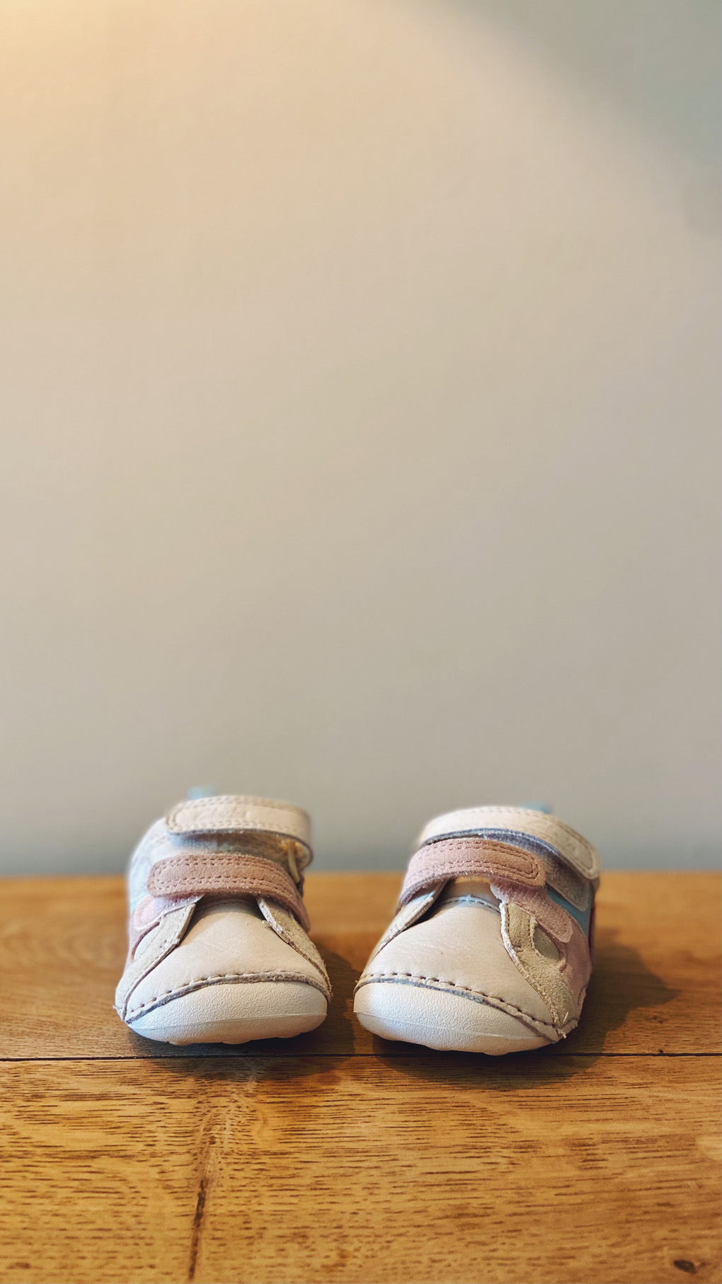 A pair of pink and white first trainers for baby girl with velcro straps