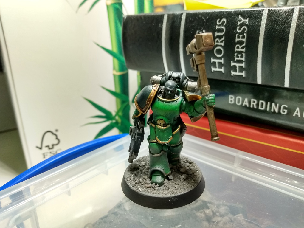 A green armoured space marine holds his hammer aloft surrounded by the tat on my desk