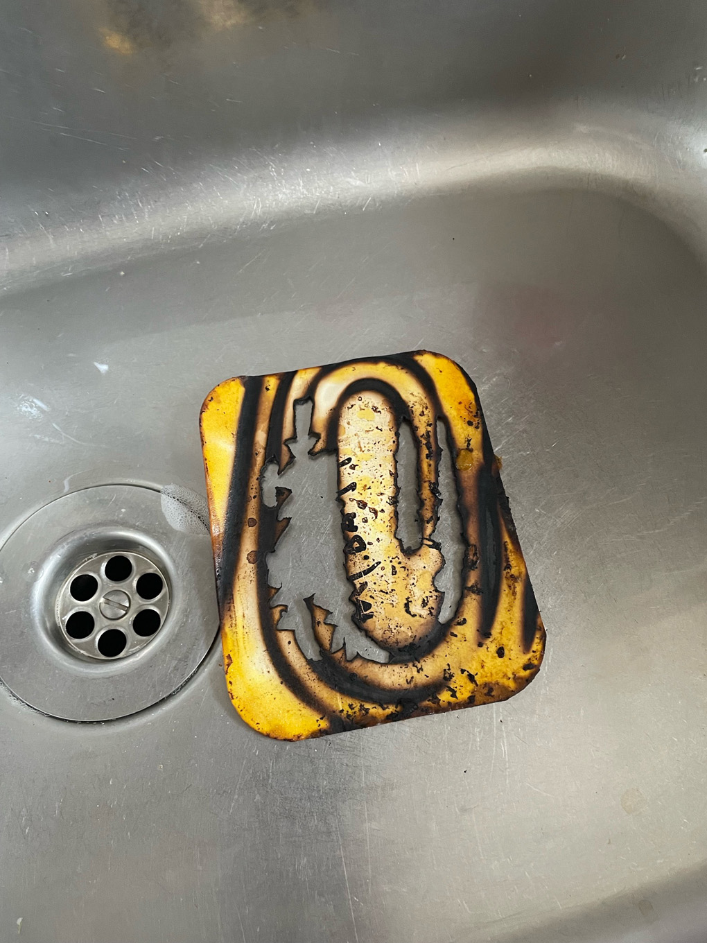 A cardboard takeaway lid with a clear ringed burn pattern from where it had caught fire in the air fryer.