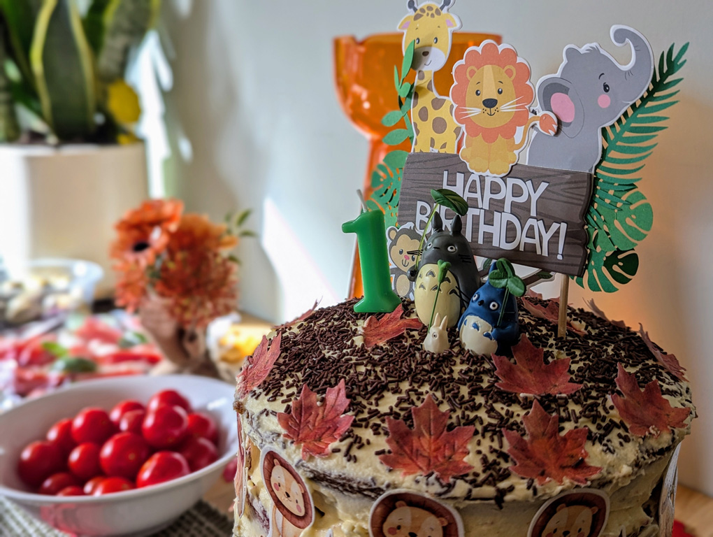 A tall birthday cake with Totoro figures balanced on the iced top