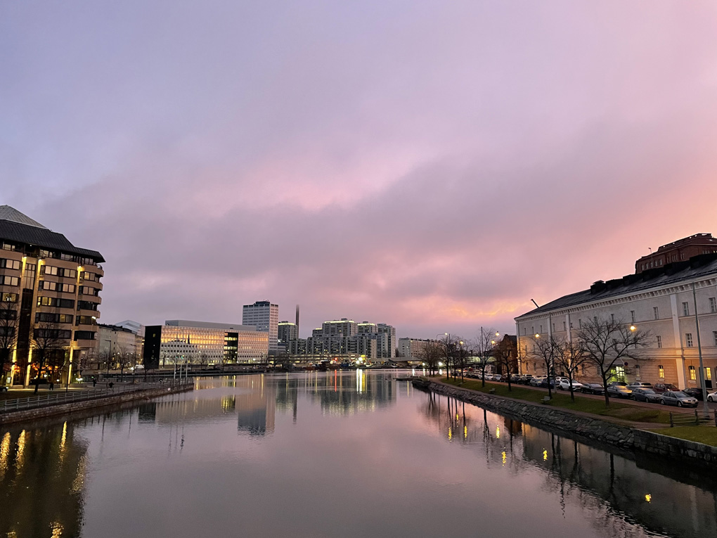 Pinkish sky over a city landscape and water.