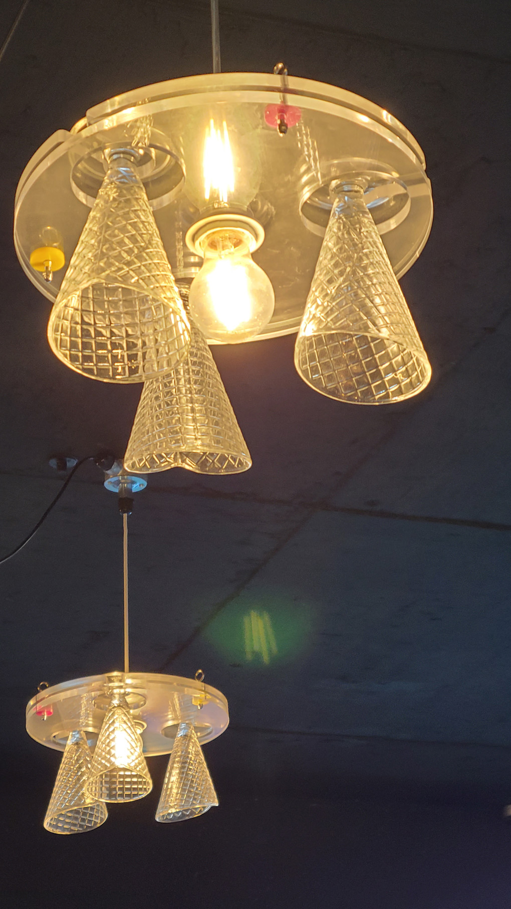 Glass waffle cone light fixtures hanging from a black ceiling