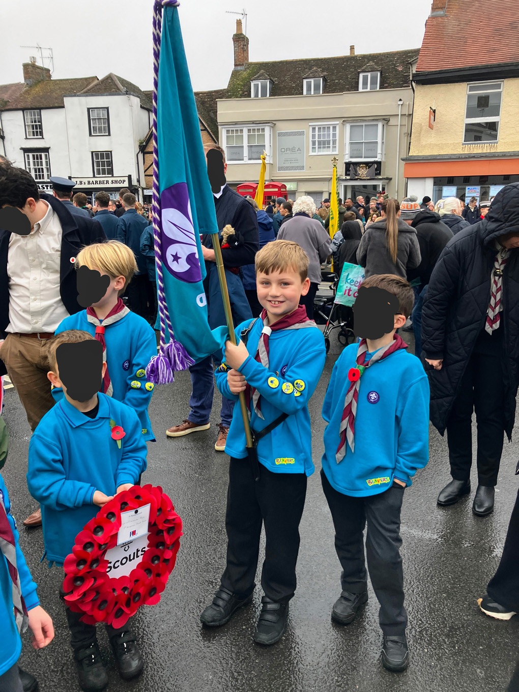 Jack holding the Beavers flag in a crowd of people before the start of the remembrance day parade. Big smiles all around!