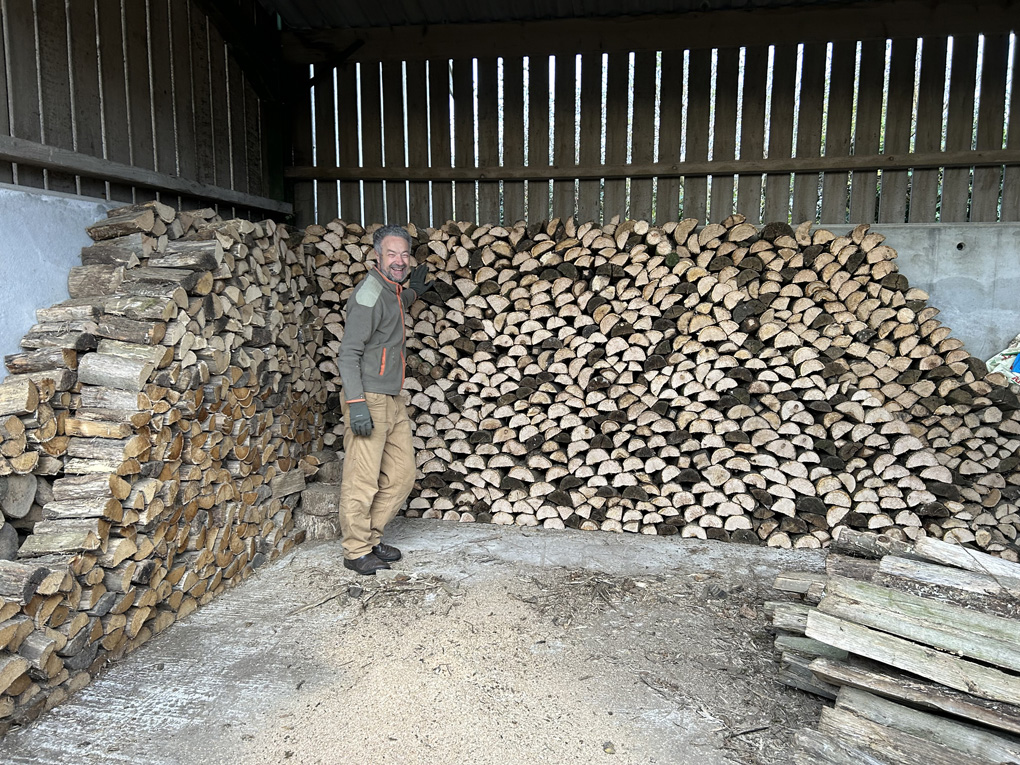 Man standing in front of a huge pile of chopped logs