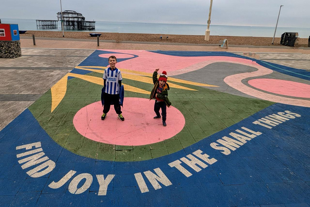 Two children standing by a caption 'Find Joy in the Small Things'