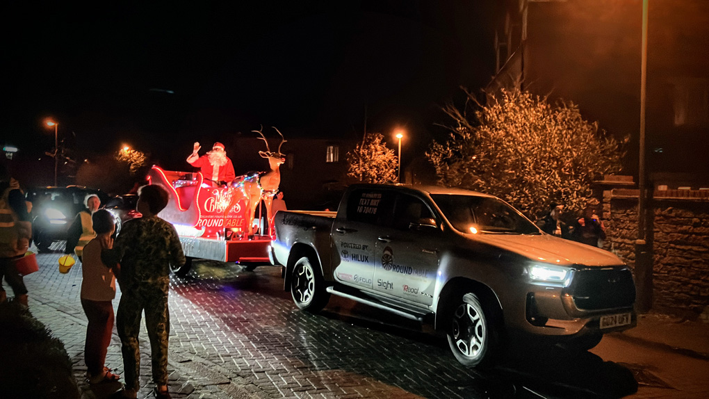 Santa on the back of a trailer with my boys excitedly watching on and waving.