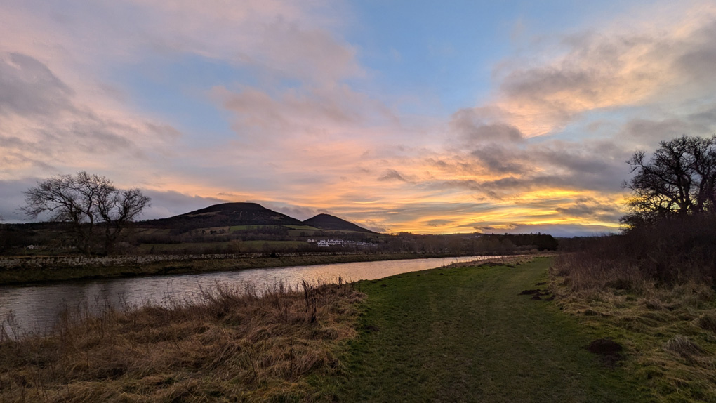 A colourful sunset over the Eildon hills with the river Tweed winding in the foreground