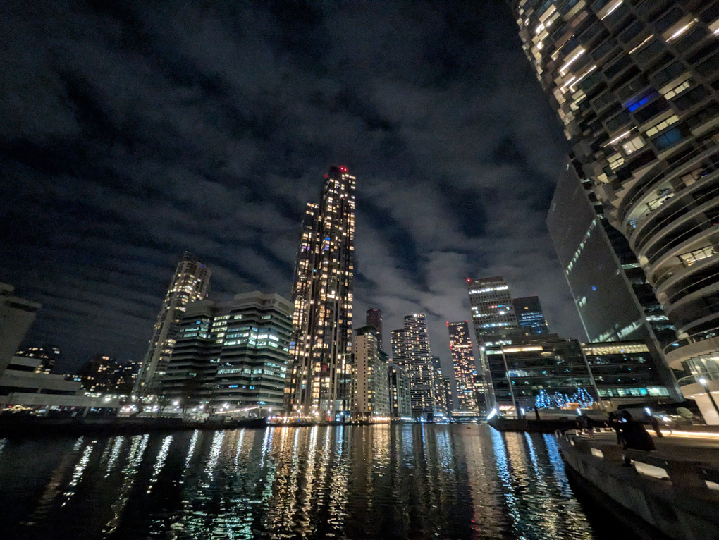 tall tower blocks with lights reflected in the water at night