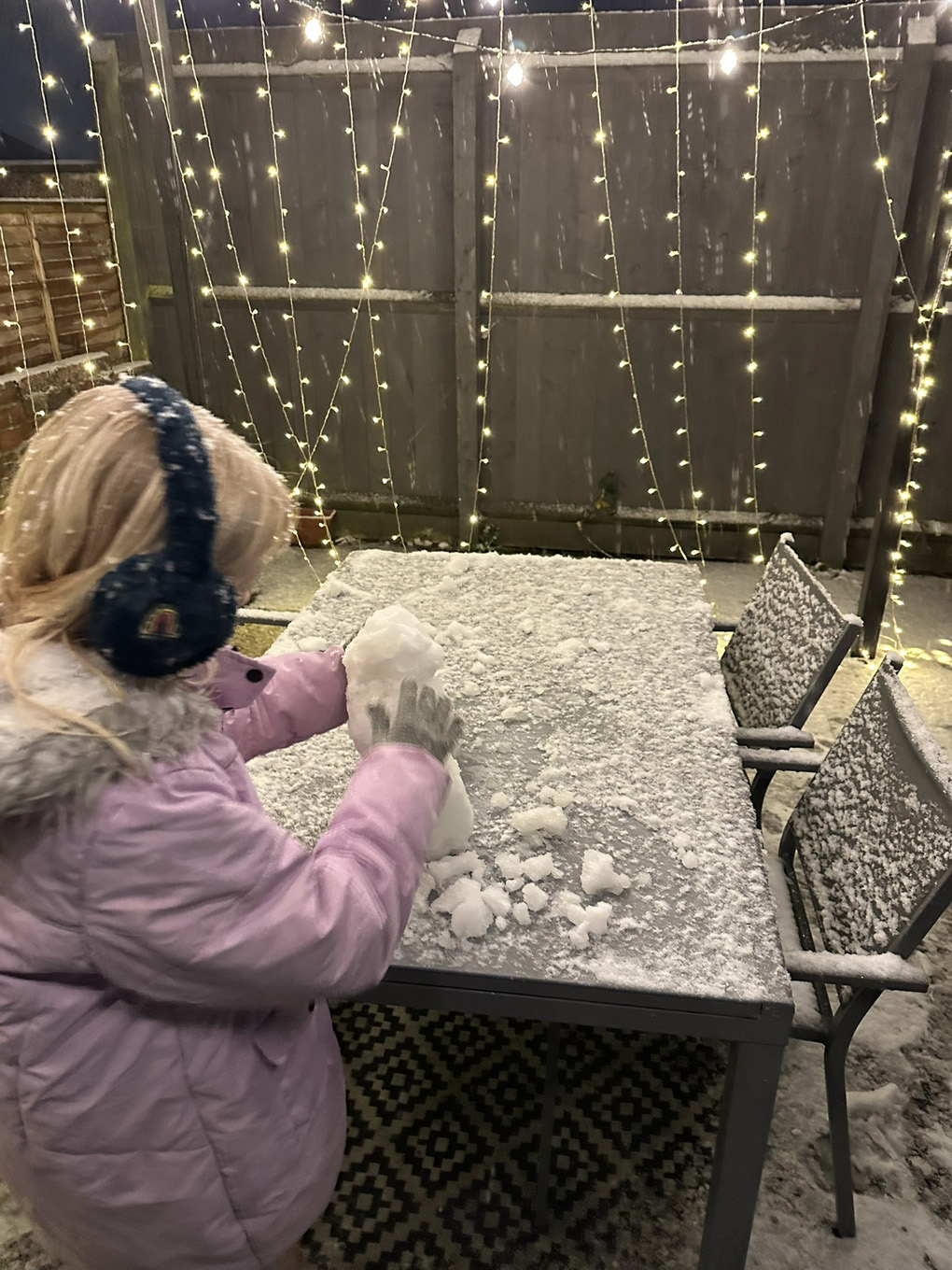 Child building a small snowman on a table.