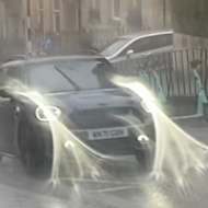 A view of a car driving up a street in Bath during torrential rain. Water has smeared the lens, leaving the picture blurry.