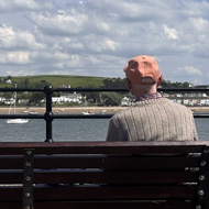 Two men sat on a bench looking out over an estuary