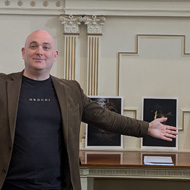 Man standing in front of photographs and a projector screen