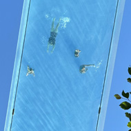 A swimming pool suspended between a couple of tall buildings. Shot from below.