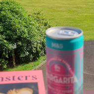 View across a green golf course with a book and drink in the foreground.