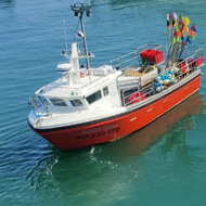 Two fishing boats landing catches on a sunny day in front of the marina