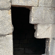 A gap in a stone wall, revealing an ominous dark space behind it