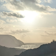 View down a valley over the sea as the sun starts to dip