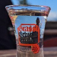 A baby's beaker on a table next to a clear small glass of alcohol