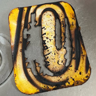 A cardboard takeaway lid with a clear ringed burn pattern from where it had caught fire in the air fryer.