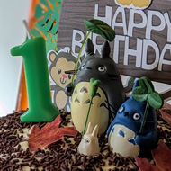 A tall birthday cake with Totoro figures balanced on the iced top