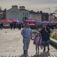 If you turn your back on the river in Greenwich by the Cutty Sark there is an open area with raised reed beds and benches for sitting and watching the Thames. There's the colourful tents of a food fair in the distance and a week autumn sun shining through a wide open sky of cloud