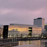 Pinkish sky over a city landscape and water.