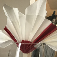 Dinning table with white table cloth, blue and white plates, wine glasses holding red and white napkins.