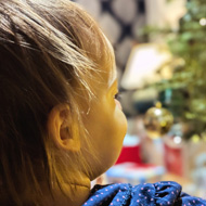 A toddler looking at a Christmas tree (out fo focus). The light reflect off her face creating a warm glow