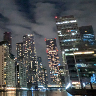 tall tower blocks with lights reflected in the water at night