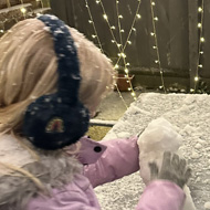 Child building a small snowman on a table.