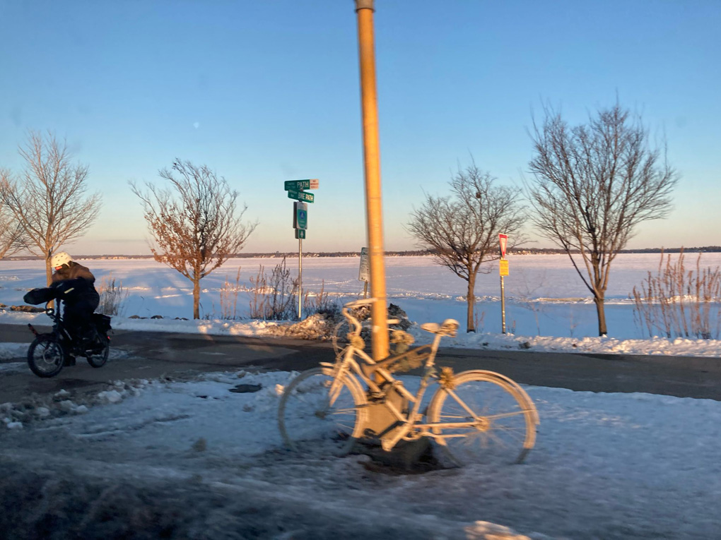 Snow covered bike leaning against a lamp post in a snow covered scene