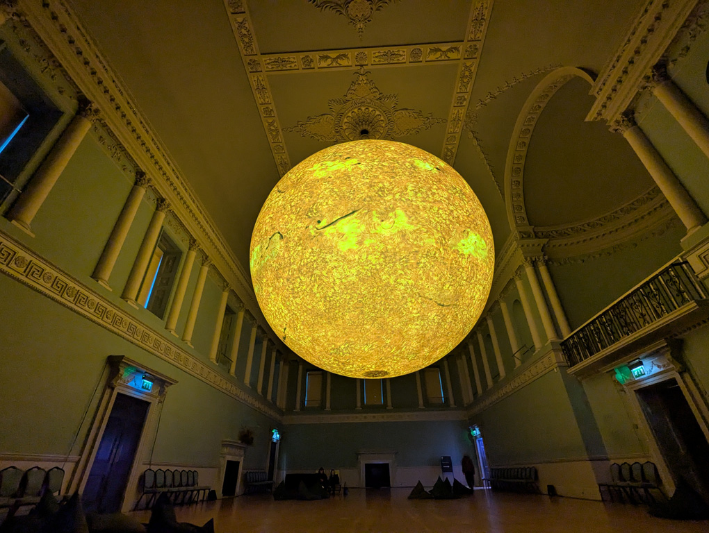 Large sculpt of the sun hanging in the middle of a Georgian hall